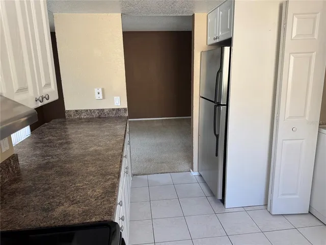 a view of a refrigerator in kitchen and an empty room