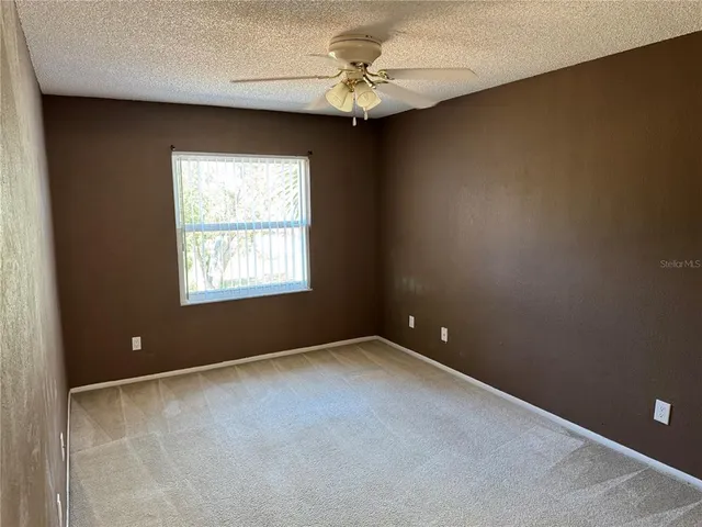 an empty room with a window and a ceiling fan