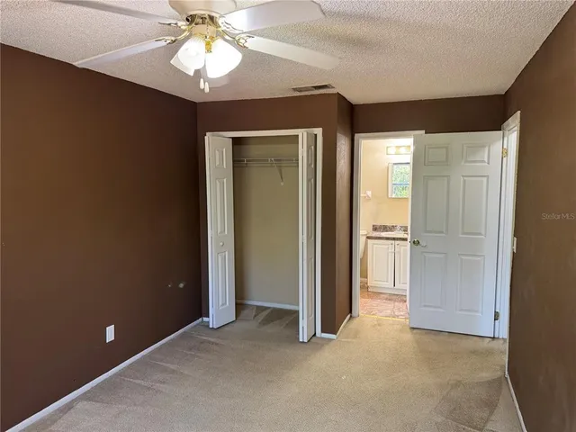 an empty room with closet and a chandelier fan