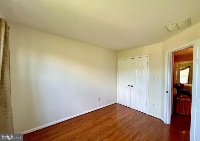 a view of an empty room with wooden floor and closet