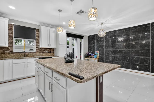 a kitchen with kitchen island granite countertop a sink a counter top space appliances and cabinets