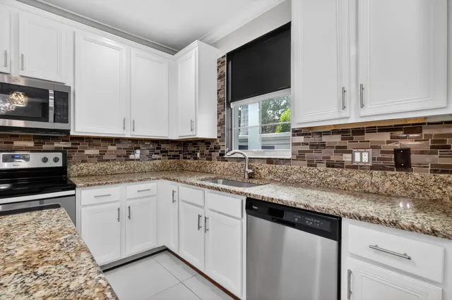 a kitchen with granite countertop white cabinets stainless steel appliances a sink and dishwasher
