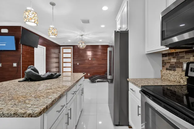 a kitchen with kitchen island a counter top space a sink stainless steel appliances and cabinets