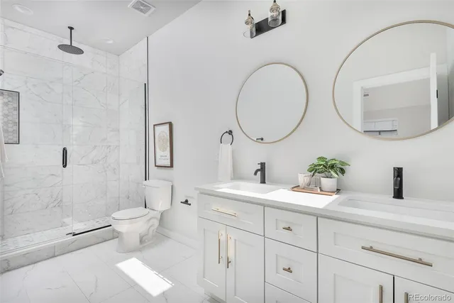 a bathroom with a toilet a sink a mirror and a shower