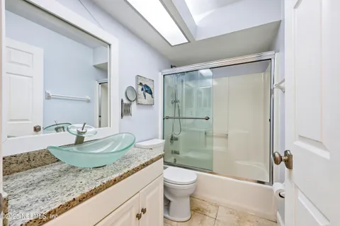 a bathroom with a granite countertop sink a toilet and shower