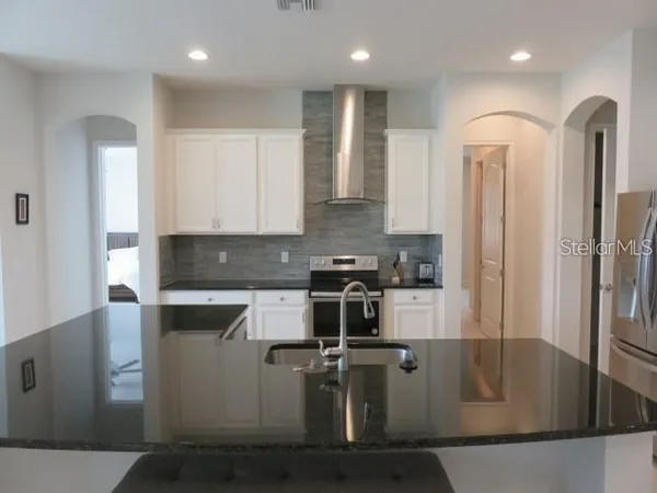 a kitchen with stainless steel appliances granite countertop a refrigerator a stove and a sink with wooden cabinets