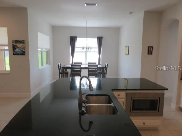 a kitchen with stainless steel appliances granite countertop a stove a sink a dining table and chairs with wooden floor