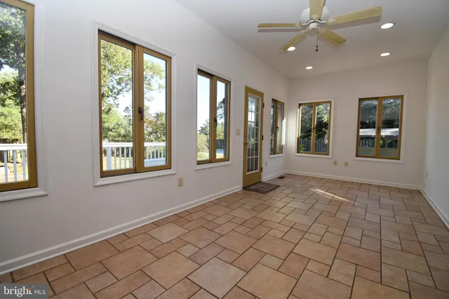 a view of an empty room with window and chandelier fan