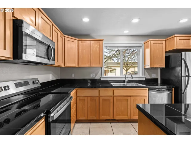 a open kitchen with stainless steel appliances kitchen island granite countertop a refrigerator a sink a stove and oven