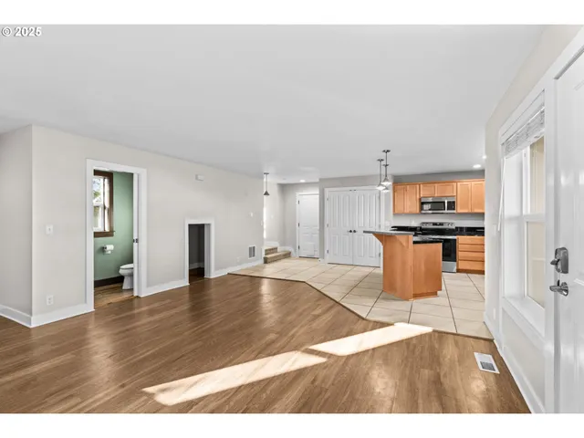 a view of an empty room with window and wooden floor
