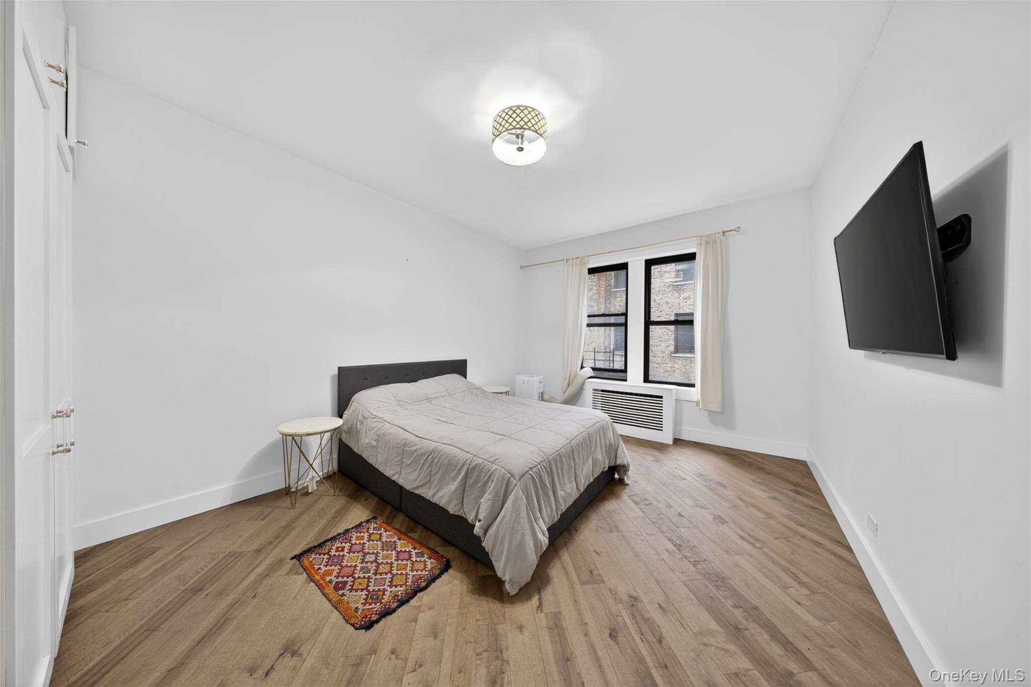 812 Riverside Drive, Unit 42 Manhattan, NY 10032 - Photo 13 of 19 a bedroom with a bed and a flat tv screen on a dresser