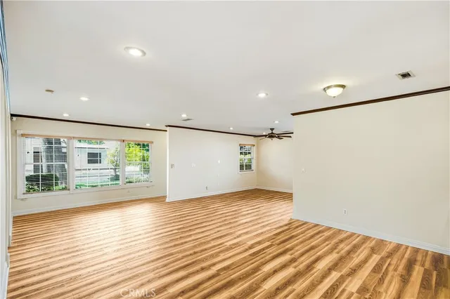 a view of empty room with wooden floor and fan
