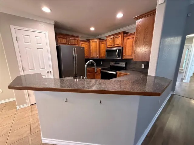 a kitchen with stainless steel appliances granite countertop a refrigerator a sink a stove and a microwave oven