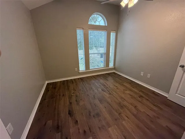 an empty room with wooden floor cabinet and windows