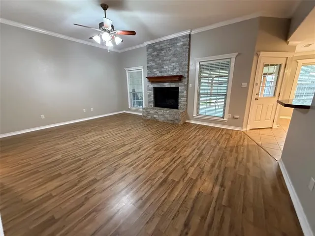 a view of an empty room with wooden floor fireplace and a window