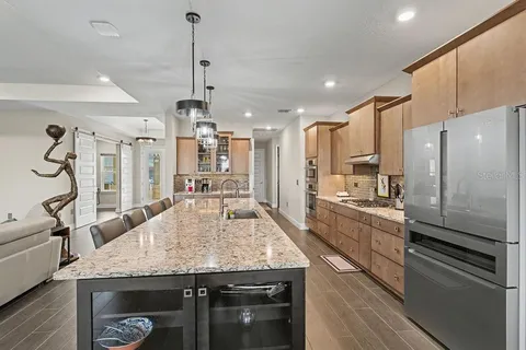 a kitchen with granite countertop kitchen island stainless steel appliances a sink cabinets and wooden floor