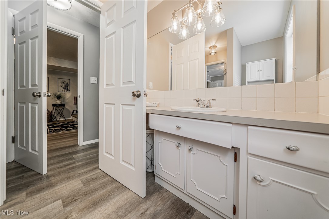 595 Moorfield Road Fairlawn, OH 44313 - Photo 36 of 50 Lower level bathroom featuring vanity, light wood-type flooring, tasteful backsplash, and a chandelier