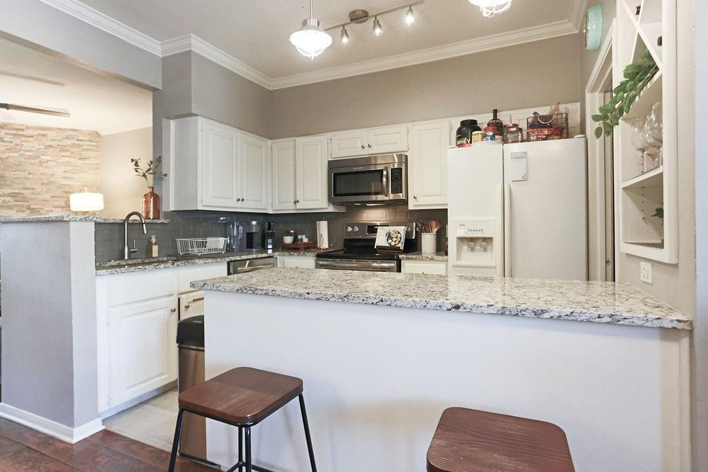 1307 Kinney Avenue, Unit 121 Austin, TX 78704 - Photo 5 of 12 a kitchen with stainless steel appliances granite countertop a stove a sink a microwave a refrigerator and white cabinets