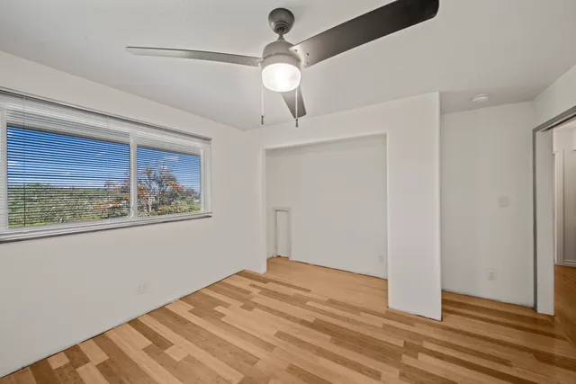 a view of empty room with wooden floor and fan