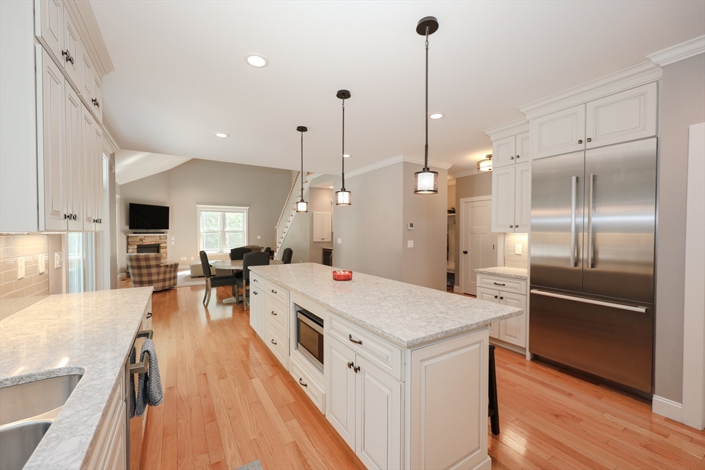 327 North Amherst Road Bedford, NH 03110 - Photo 8 of 39 a large kitchen with kitchen island a stove a sink a refrigerator and a wooden floor