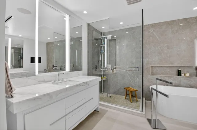 a bathroom with a sink double vanity granite tub shower and a mirror