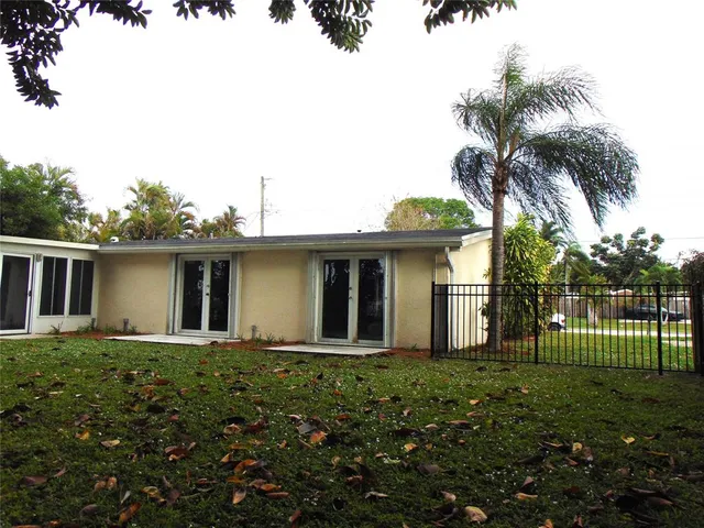 a view of a swimming pool with a yard and palm trees