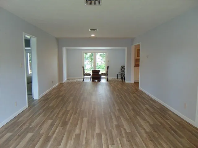 a view of a big room with wooden floor and a window
