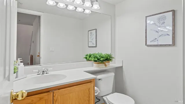 a bathroom with a granite countertop sink a toilet and mirror