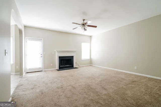 an empty room with windows and fireplace
