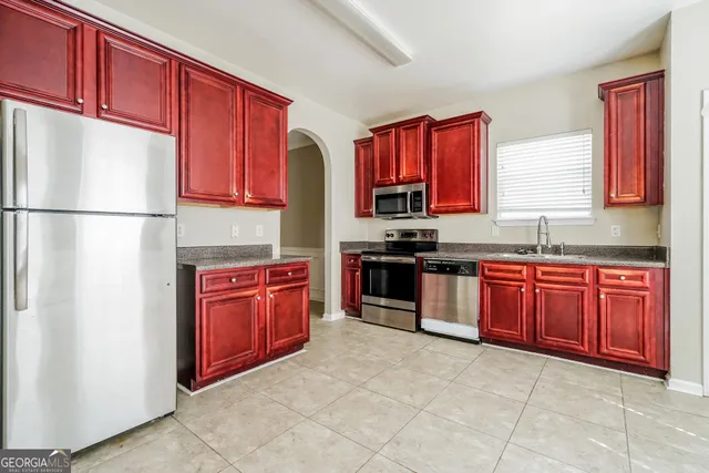 a kitchen with stainless steel appliances granite countertop a refrigerator sink and wooden cabinets