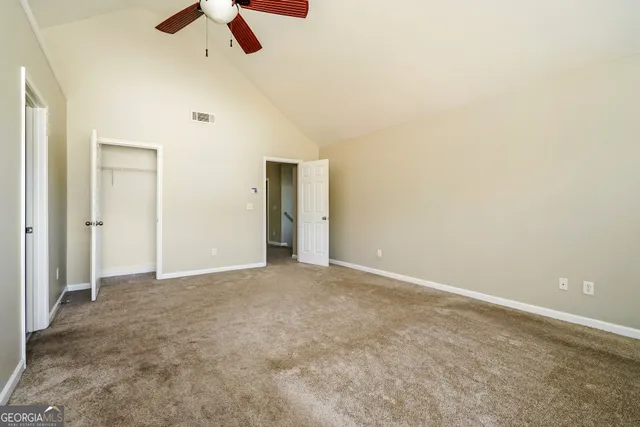 an empty room with ceiling fan and window