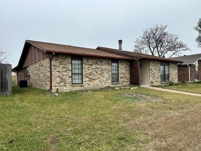 Single story home featuring a front yard, board and batten siding, and brick siding