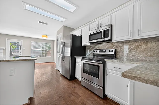 a kitchen with stainless steel appliances granite countertop a stove a microwave and a hard wood floors
