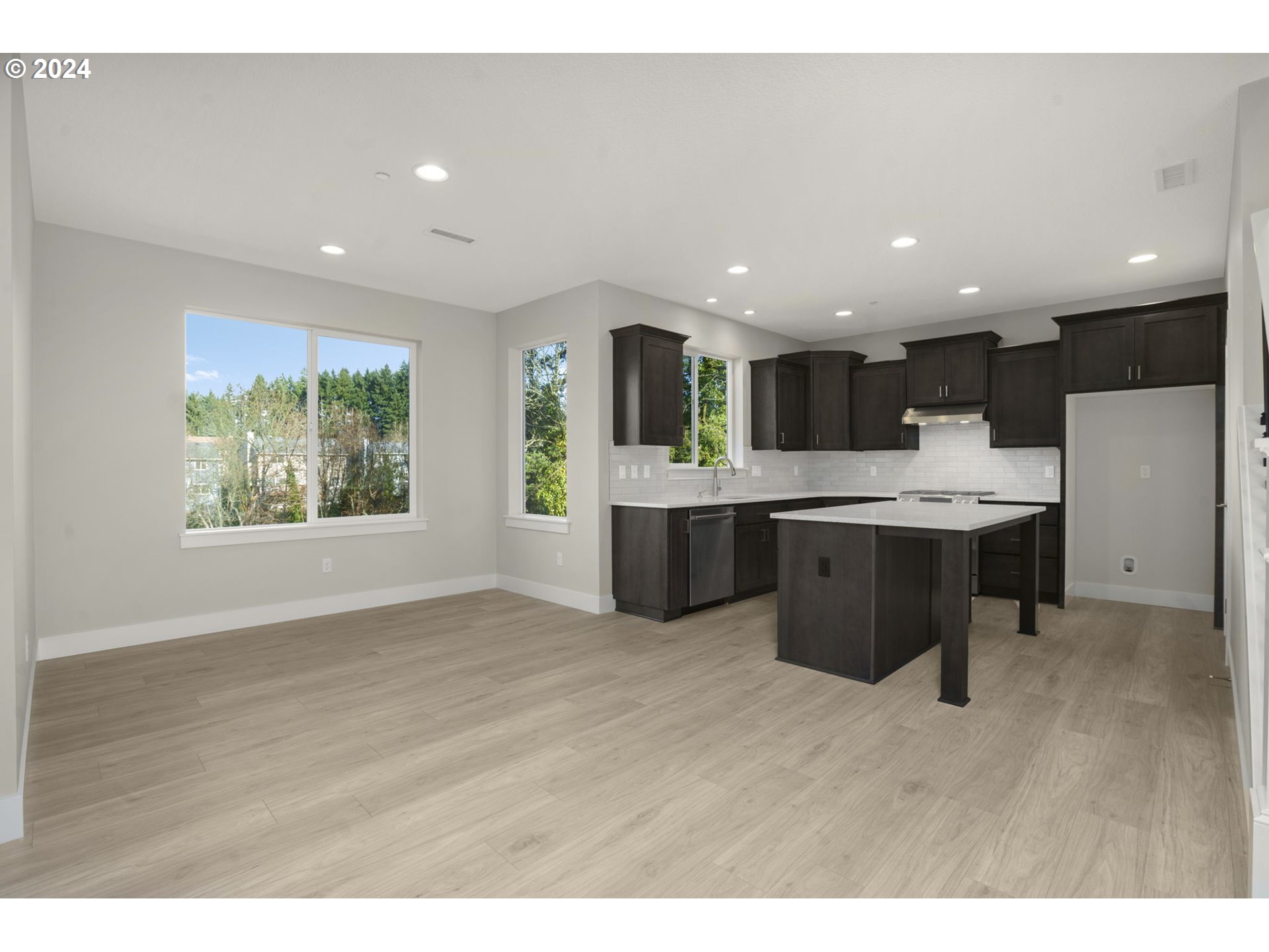 7233 Northeast Ridge Drive Hillsboro, OR 97124 - Photo 7 of 24 a open kitchen with kitchen island a stove a sink a refrigerator and a dining table with wooden floor