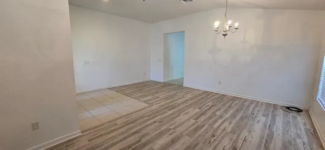 wooden floor in an empty room with a chandelier