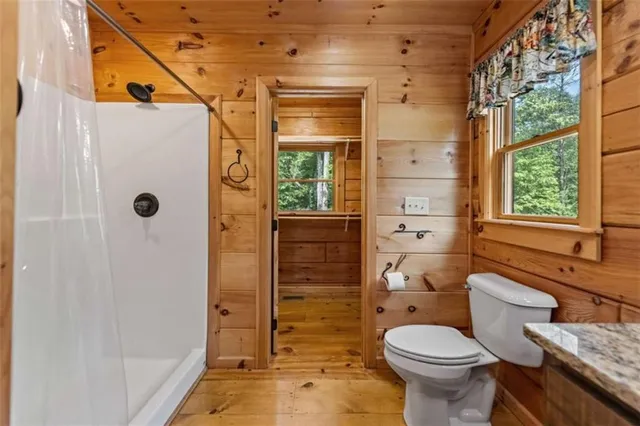 a bathroom with a toilet a window and shower