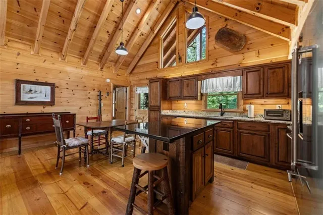 a kitchen with stainless steel appliances granite countertop a refrigerator a sink dishwasher a dining table and chairs with wooden floor