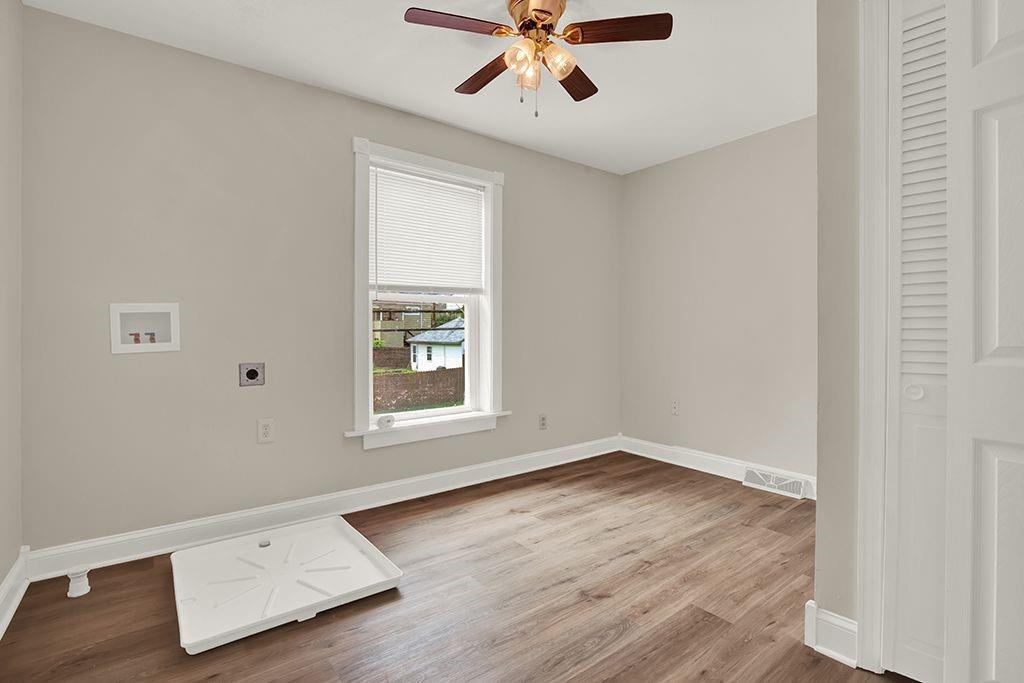 62 1st Street Irwin, PA 15642 - Photo 19 of 27 an empty room with wooden floor chandelier fan and windows