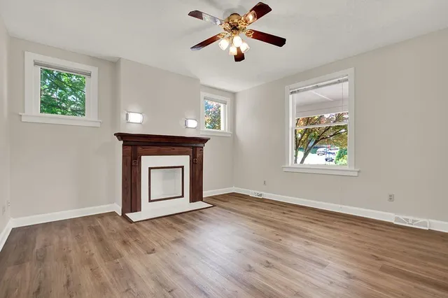 a view of an empty room with window and wooden floor