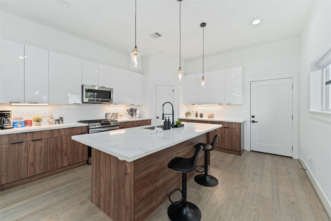 3034 Gray Street, Unit B Houston, TX 77004 - Photo 3 of 23 a kitchen with kitchen island a sink dining table and chairs