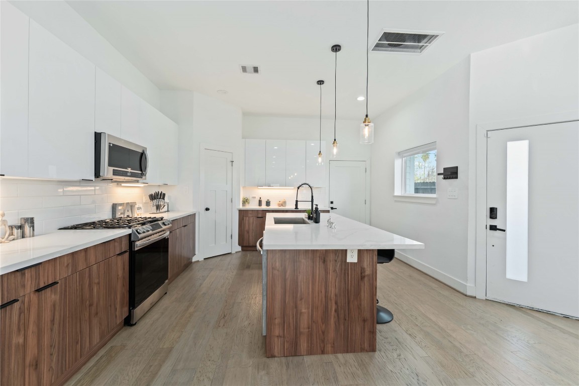 3034 Gray Street, Unit B Houston, TX 77004 - Photo 5 of 23 a large kitchen with cabinets wooden floor and stainless steel appliances
