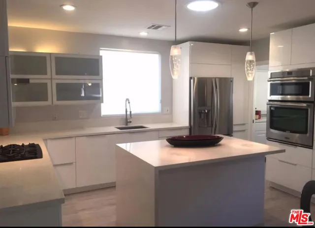 a kitchen with kitchen island a sink appliances and a counter top space