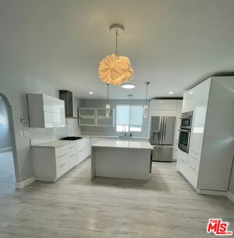 a large white kitchen with a large window appliances and cabinets