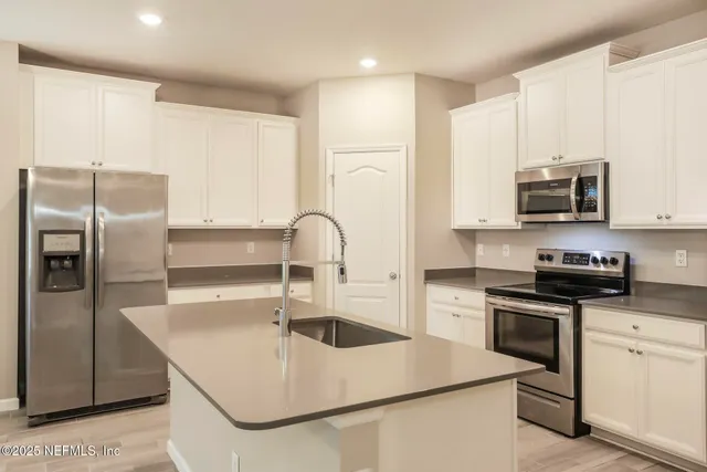 a kitchen with stainless steel appliances granite countertop a sink a stove and a refrigerator