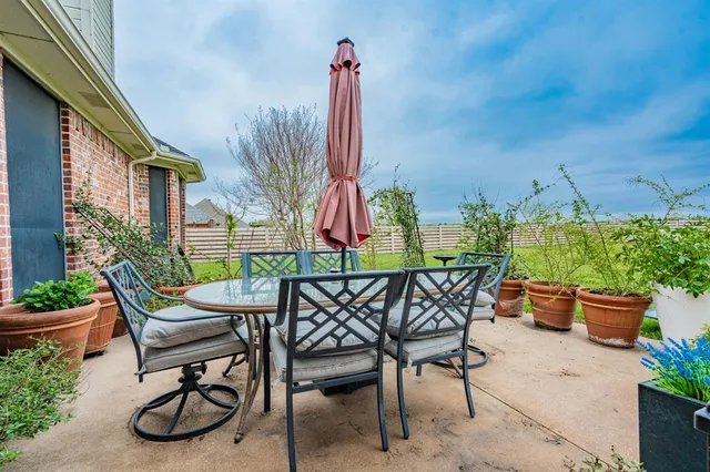 a patio with a table and chairs potted plants