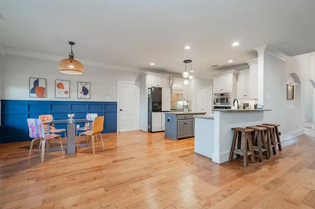 a kitchen with stainless steel appliances a dining table chairs and white cabinets