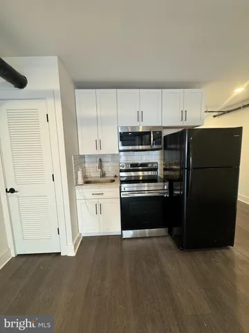 a kitchen with a refrigerator and white cabinets