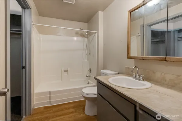 a bathroom with a granite countertop sink toilet a mirror and shower