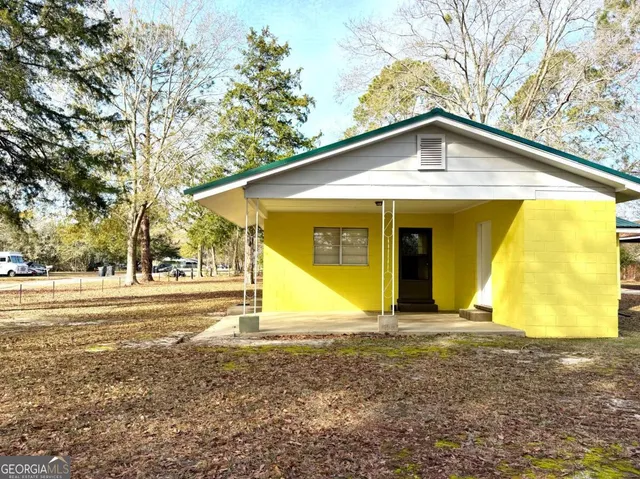a view of a house with backyard and trees