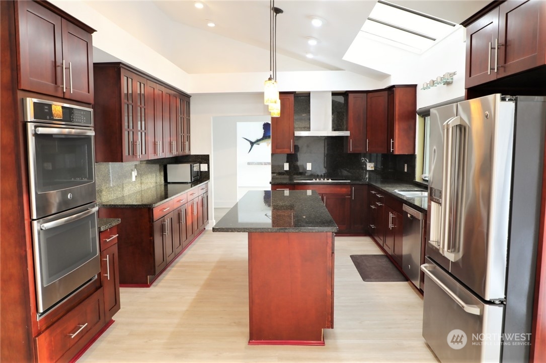 a kitchen with stainless steel appliances granite countertop a refrigerator a sink and wooden cabinets